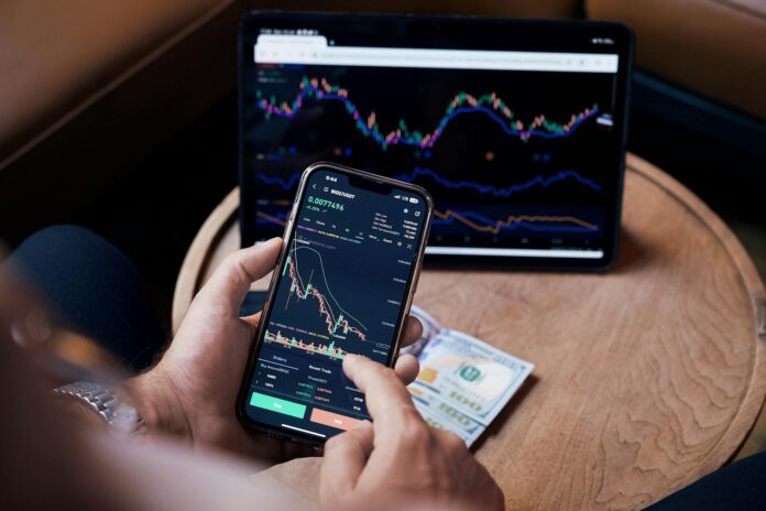 pexels-photo-17781649 man looking at the stock charts on the phone and tablet